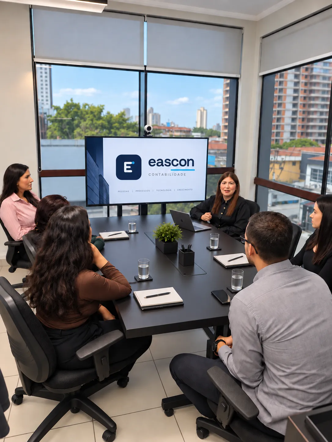 Pessoas em reunião no escritório da Eascon, com o logotipo atual na tela
